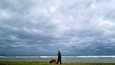 Koiranulkoiluttaja käveli rannalla Poncessa Puerto Ricossa sunnuntaina 18. syyskuuta Fiona-myrskyn lähestyessä mereltä.