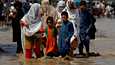 Pakistanissa kesäkuussa alkaneet tuhoisat monsuunisateet ja niistä aiheutuvat tulvat ovat peittäneet jopa kolmanneksen maasta veden alle. Kuvassa perhe kävelee tulvivalla tiellä Nowsherassa Pakistanissa 30. elokuuta 2022. 