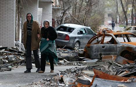 Paikalliset kävelivät tuhoutuneiden autojen ohi Mariupolissa Ukrainassa torstaina 21. huhtikuuta.