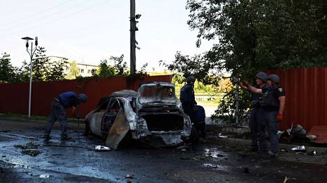 Poliisit tarkastelivat autoa, joka tuhoutui Venäjän ilmaiskussa Harkovassa Ukrainassa 8. elokuuta.