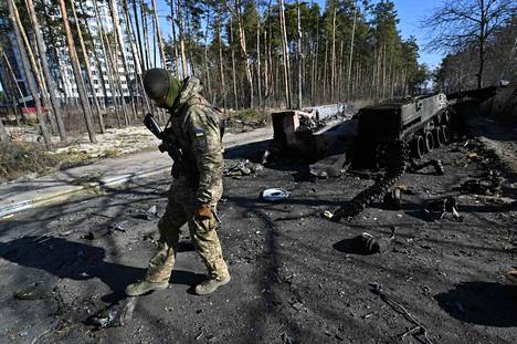 Ukrainan sotilas seisoi tuhoutuneen venäläisen panssariajoneuvon vieressä Irpinissä.