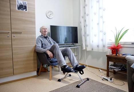 Lasse Grönroos on sinnikkäästi kuntouttanut itseään sairauskohtauksen jälkeen. Hän on noussut pyörätuolista omille jaloilleen. ”Aloitin polkemalla tällä laitteella”, Grönroos kertoo nyt omassa huoneessaan Viljavainion yhteisöasumisen yksikössä.