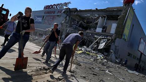 Paikalliset siivoavat venäläisten pommituksissa tuhoutuneen kauppakeskuksen ympäristöä Ukrainan Harkovassa 8. kesäkuuta 2022. 