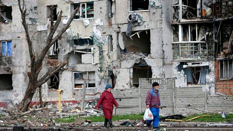 Ihmisiä pommituksissa tuhoutuneen asuinrakennuksen edustalla Mariupolin kaupungissa Ukrainassa 22. huhtikuuta.