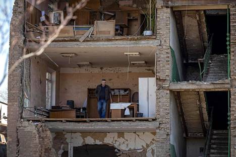 Mies seisoo Kiovan esikaupunkialueella rakennuksessa, jonka julkisivu on romahtanut 15. huhtikuuta 2022 venäläisten yön aikana tapahtuneiden iskujen jälkeen.