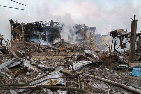 Pelastuslaitoksen työntekijät koittivat sammuttaa ilmaiskussa tuhoutuneen kenkätehtaan paloa Dniprossa.