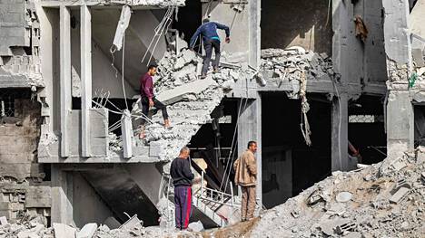 Ihmiset tutkivat osittain romahtaneen rakennuksen raunioita Gazassa 18. huhtikuuta.