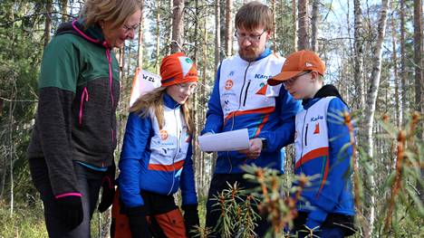 Satu, Aino, Sami ja Paavo Salomaa tutkivat yhdessä lähimetsän suunnistuskarttaa.