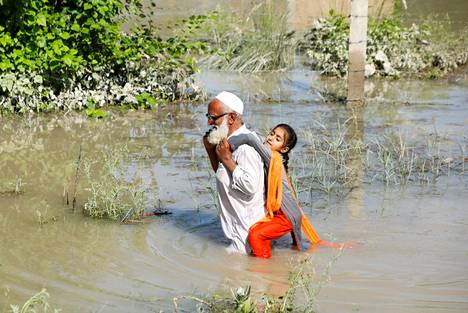 Pakistan on julistanut tulvien vuoksi kansallisen hätätilan. Kuvassa isä kantaa tytärtään tulvien peittämässä Chārsaddissa Pakistanissa 28. elokuuta 2022.