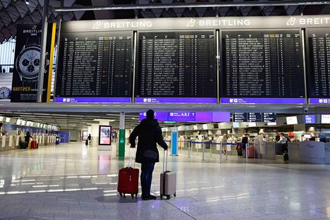 Yksinäinen matkustaja hiljaisella Frankfurtin lentoasemalla perjantaina. Valtaosassa  lähtötaulun lennoista luki: peruttu.