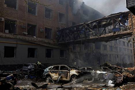 Palaneita autoja Venäjän pommituksessa tuhoutuneen rakennuksen edessä Harkovan kaupungissa 16. huhtikuuta.
