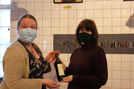 Loviisa Badermann (oik.) lahjoitti viinipullon, jonka Werstaalla vastaanotti yleisöpalvelupäällikkö Anne Lahtinen.