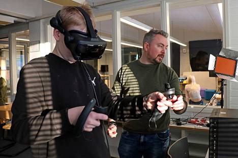 Kuvataiteenopettaja Ilkka Vuojala (oik.) auttoi yhdeksäsluokkalaista Elias Salosta pääsemään alkuun, kun hän laittoi VR-lasit päähänsä ensimmäistä kertaa. 