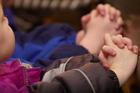 Lapset kädet ristissä päiväkotiryhmän kirkkokäynnillä.