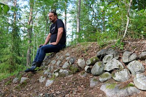 Mikko Mäkelä istuu muinaisetntuulimyllyn alustalla. Hän arvioi, että kartanon mylly on ollut iso osa alueen sen aikaista teollista keskittymää