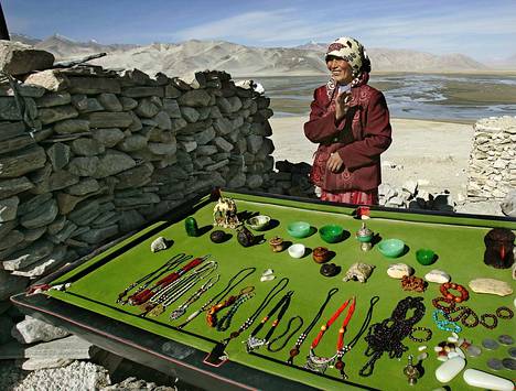 Uigurinainen on levittänyt myyntikojunsa biljardipöydälle Taivaan vuorten halki kulkevan Karakum-highwayn varteen.