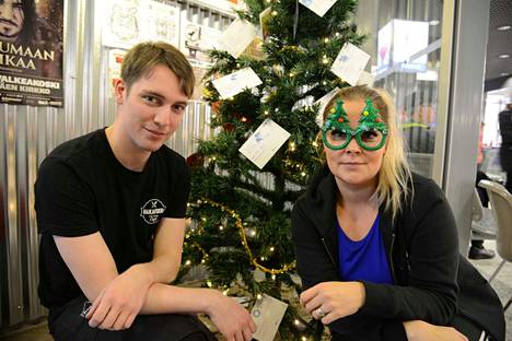 Jere Lehojärvi ja Jenni Jakka ovat Torikeskuksen joulupuun äärellä ja keräyksessä mukana lämpimällä joulunalushengellä.