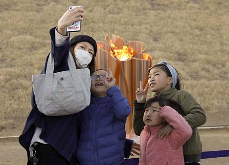 Perhe ottaa kuvaa olympiatulen edessä. Olympiatuli saapui Japaniin perjantaina.