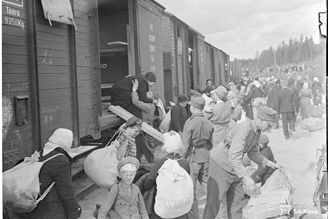 Sotavirkailija Orko nostaa siirtolaisia alas vaunusta Vilppulassa. SA-kuvat