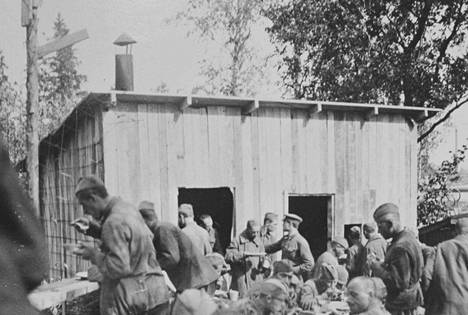 Ruokailuhetki Valkeakosken sotavankileirin keittiön virkaa toimittaneen tönön edustalla. Leirin päällikön määräyksestä vangit valmistivat ruokansa itse, mikä saattoi olla yksi syy vankien nääntymiseen. Useilla muilla leireillä muonituksesta vastasivat lotat.