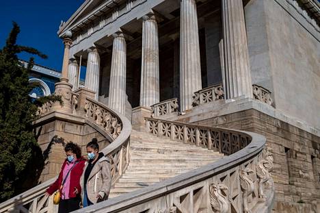 Kasvomaskein suojautuneita ihmisiä Kreikan kansalliskirjaston portailla torstaina Ateenassa.