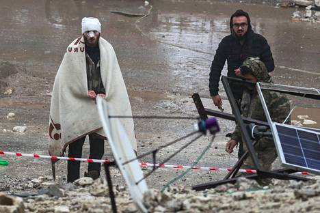 Loukkaantunut mies ja hänen vierellään kulkeva pelastusviranomainen etsimässä maanjäristyksestä selviytyneitä Jandarissa Syyriassa.