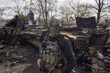 Ukrainalaissotilas käveli tuhotun venäläisen panssarivaunun editse lähellä Kiovaa sunnuntaina.