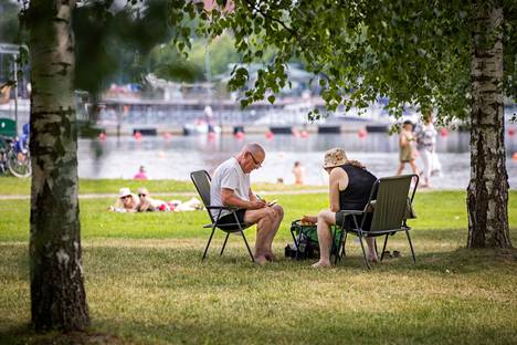 Ulla ja Olli Hammais rentoutuivat Kirjurinluodossa puiden katveessa tuulenvireestä nauttien hellepäivänä 27. kesäkuuta.