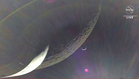 Kuvakaappauksessa Orion-kapselista kuvatulta videolta näkyy Maa sirppinä Kuun takana.