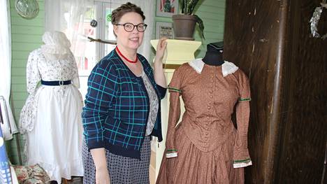 Pukuharrastaja Meri Kortteenpohja itsetekemiensä pukujen keskellä: vaalea puku vasemmalla on 1700-luvun puku ja ruskea puku oikealla on 1800-luvun muotia.