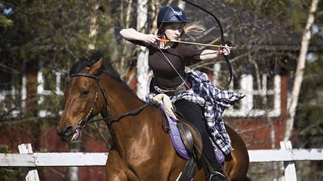 Tiia Salminen ampumassa Jenni-hevosen selästä. Salminen oli harrastanut pitkään sekä ratsastusta että jousiammuntaa. Ratsastusjousiammunnassa hän pääsee yhdistämään kaksi itselleen rakasta lajia. 