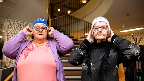 Maarit Kervinen (vasemmalla) seuraa innokkaasti jääkiekkoa. Annele Heino sanoo, ettei ymmärrä jääkiekosta mitään. Kumpikin on mukana neulomassa MM-kisatuotteita. 