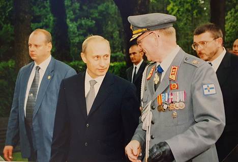 Helsingin sotilasläänin komentaja kenraalimajuri Ahti Vartiainen isännöi Vladimir Putinin käyntiä Hietaniemen hautausmaalla vuonna 2001. Miehet kävivät keskinäiset keskustelunsa englannin kielellä.