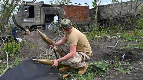 Ukrainalainen sotilas tutki Venäjän joukkojen jälkeensä jättämiä ammuksia ja ajoneuvoja Mala Roganin kylässä Harkovan lähistöllä perjantaina