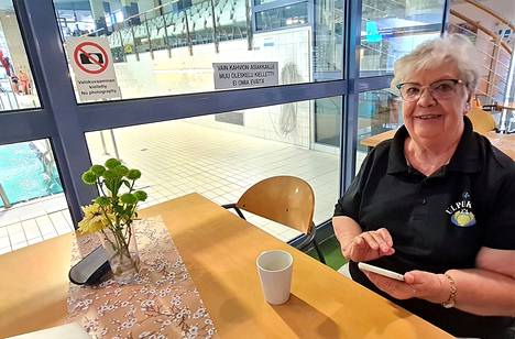 Seija Meriläinen kahviossaan, jota hän on pitänyt yli 25 vuotta. Hän hakee puhelimestaan lakimiehensä Timo Tavion puhelinnumeroa. Tarvetta on.