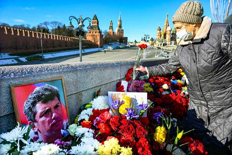 Ihmiset laskevat kukkia sillalle, jossa oppositiopoliitikko Boris Nemtsovia ammuttiin seitsemän vuotta sitten. Paikka sijaitsee lähellä Kremliä Moskovassa. Kuva on otettu 27. helmikuuta 2022. 