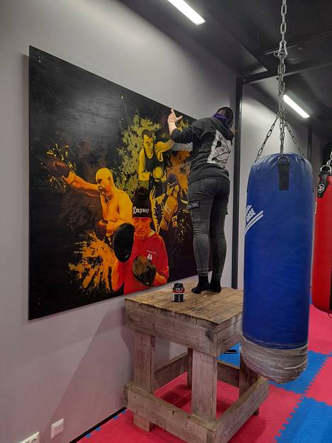 Petra Holkko viimeistelemässä maalausta, johon on kuvattu menestyneitä paikallisia nyrkkeilijöitä.