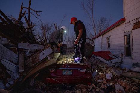 Miehet siivosivat poistivat roskia ajoneuvonsa päältä tornadon jälkeen Yhdysvaltain Kentuckyssa sunnuntaina.
