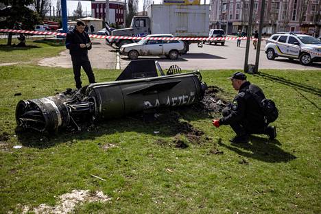 Ukrainalaiset poliisit tutkivat ohjuksen jäännöksiä Kramatorskin aseman lähistöllä perjantaina. Ohjuksen kylkeen on kirjoitettu venäjäksi ”lasten puolesta”.