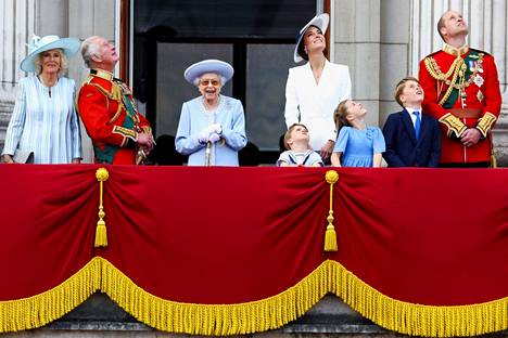 Kuningattaren perilliset ovat jo pitkään edustaneet hänen kanssaan. Kuningatar Elizabeth, Prinssi Charles, Cornwallin herttuatar Camilla, Prinssi William ja Cambridgen herttuatar Catherine sekä Prinsessa Charlotte, Prinssi George and prinssi Louis tervehtivät kansaa parvekkeelta seuratessaan kuningattaren jubileum-juhlan Trooping the Colour -paraatia kesäkuussa 2022.
