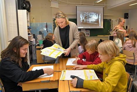 Luokaopettaja Laura Salmi kertoo Unto Vireelle (vas.), Kristian Tuomiselle ja Oskar Bindarille vanhoista materiaaleista. 