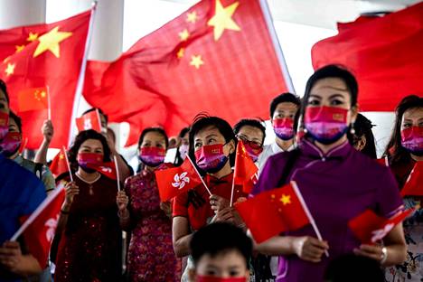 Hongkongissa on perjantaina juhlittu siirtoa Britannialta Kiinalle 25 vuotta sitten. Viranomaiset ovat pyrkineet antamaan kuvan, että merkkipäivän juhlinnalla on Hongkongissa julkinen tuki. Kuvassa ihmiset pitivät kiinan lippuja ja lauloivat juhlan kunniaksi.