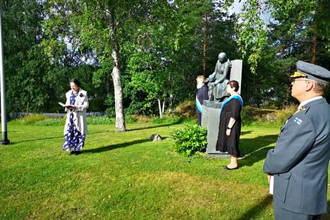 Sukuyhdistyksen puheenjohtaja Inkeri Haarla-Kettunen laski airuiden vartioiman Äiti-patsaan juurelle sinivalkoisen kukkavihkon. 
