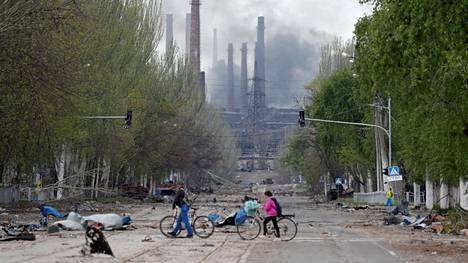 Ihmiset taluttivat polkupyöriään Ukrainan Azovstalin tehtaan lähellä tiistaina 2. toukokuuta.