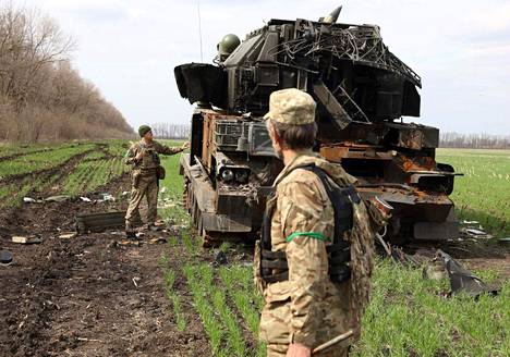 Ukrainalaissotilaat tuhotun venäläisen panssariajoneuvon luona 16. huhtikuuta Itä-Ukrainassa, lähellä Gusarovkan kylää.