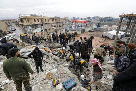 Joukko asukkaita ja pelastustyöntekijöitä sortuneella talolla Jandarisissa.