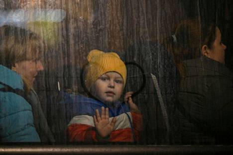 Ukrainalaislapsi vilkuttaa bussin ikkunasta päästyään Ukrainasta Puolan puolelle.