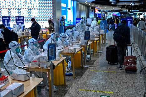 Terveydenalan työntekijät odottivat matkailijoita koronatestattaviksi rautatieasemalla Shanghaissa tiistaina 6. joulukuuta.