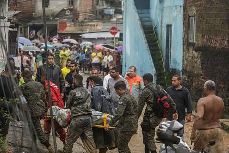 Miehet kantoivat rankkasateiden aiheuttaman maanvyörymän vuoksi romahtaneesta talosta löytynyttä ruumista Recifen kaupungissa Brasiliassa 28. toukokuuta 2022.