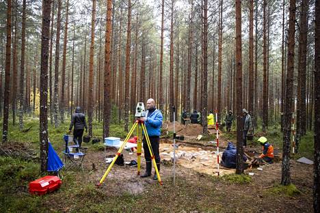 Kaivauspaikka sijaitsee hiljaisessa mäntymetsässä. Etualalla kaivauksen toinen vetäjä Janne Soisalo  laittaa takymetriä mittauskuntoon.